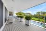 Wooden deck featuring an outdoor pool, view of scattered trees, and grilling area