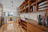 Bar with light wood-style flooring, open shelves, and pendant lighting