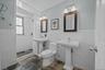 Full bath featuring tile walls, a shower stall, wainscoting, and stone tile floors