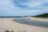 Scenic shoreline view with sandy beach, gentle waves, and a natural coastal inlet, showcasing the unspoiled waterfront setting and expansive horizon b
