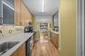 Kitchen featuring glass insert cabinets, stainless steel range with gas stovetop, light wood-type flooring, decorative backsplash, and dishwasher
