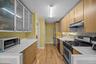 Kitchen with glass insert cabinets, appliances with stainless steel finishes, light wood finished floors, under cabinet range hood, and decorative bac