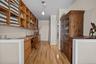 Bar area featuring dark countertops, light wood finished floors, open shelves, decorative light fixtures, and built in study area