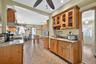 Kitchen featuring decorative light fixtures, glass insert cabinets, inlaid floor details, brown cabinetry, and light tile patterned floors