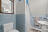 Bathroom with tile walls, a baseboard radiator, wainscoting, vanity, and curtained shower