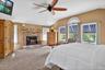 Carpeted bedroom featuring lofted ceiling, a fireplace, and a ceiling fan