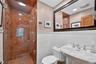 Main Floor Full bathroom featuring a stall shower, tile walls, and a wainscoted wall