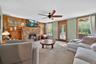 Living area with carpet flooring, wood walls, a baseboard heating unit, a ceiling fan, and a fireplace