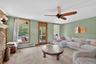 Carpeted living area featuring a baseboard radiator, plenty of natural light, a ceiling fan, and a fireplace