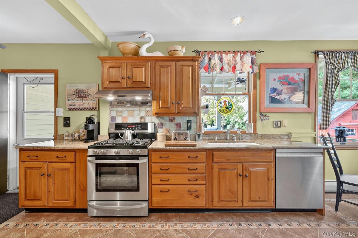 Kitchen with stainless steel appliances, backsplash, under cabinet range hood, light stone countertops, and recessed lighting