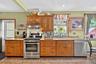 Kitchen with stainless steel appliances, backsplash, under cabinet range hood, light stone countertops, and recessed lighting