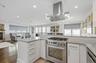 Kitchen with white cabinetry, island range hood, ornamental molding, appliances with stainless steel finishes, and a fireplace