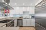 Kitchen with island range hood, backsplash, a sink, white cabinets, and appliances with stainless steel finishes