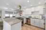 Kitchen featuring stainless steel appliances, island exhaust hood, a sink, white cabinets, and a peninsula