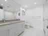Full bath with marble finish floor, a sink, visible vents, and baseboard heating