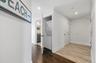 Hall with ornamental molding, wood finished floors, stacked washing maching and dryer, and recessed lighting