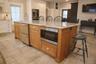 Kitchen featuring sink, white cabinetry, double oven, a large island, and light stone countertops