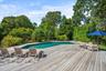 Swimming pool with a deck, grilling area, and view of wooded area