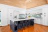 Kitchen featuring open shelves, a breakfast bar area, white cabinets, a spacious island, and wooden ceiling