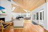 Living room with vaulted ceiling, a warm lit fireplace, plenty of natural light, and wood flooring