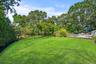 View of green lawn with view of wooded area