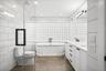 Primary full bath with tile walls, double vanity, a soaking tub