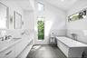 Full bathroom featuring double vanity, a freestanding tub, dark tile patterned flooring, tile walls, and a wainscoted wall