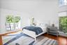 Bedroom with multiple windows, high vaulted ceiling, wood finished floors, and access to outside