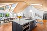 Kitchen featuring cabinetry, a skylight, wood finished floors, appliances with stainless steel finishes, and light stone counters