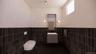 Half bathroom with tile walls, vanity, wainscoting, and dark tile patterned flooring