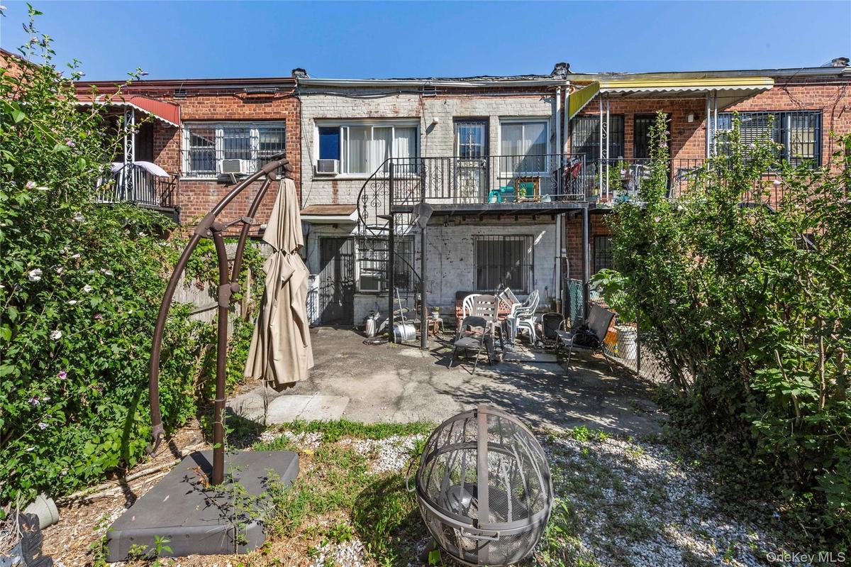 Back of house featuring brick siding, a balcony, a patio area, and stairs