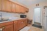 Kitchen with black microwave, freestanding refrigerator, backsplash, light countertops, and brown cabinets