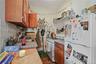 Kitchen featuring white appliances, light countertops, open shelves, tasteful backsplash, and brown cabinetry