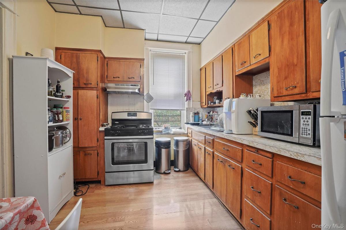 Kitchen featuring a paneled ceiling, appliances with stainless steel finishes, light countertops, backsplash, and light wood-style floors