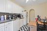Kitchen with tile patterned floors, stainless steel microwave, white cabinetry, decorative backsplash, and a ceiling fan