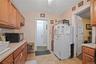 Kitchen with black microwave, freestanding refrigerator, light countertops, brown cabinetry, and backsplash