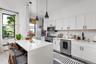 Kitchen with white cabinetry, hanging light fixtures, backsplash, appliances with stainless steel finishes, and light stone countertops