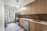Kitchen featuring appliances with stainless steel finishes, backsplash, modern cabinets, light tile patterned floors, and hanging light fixtures