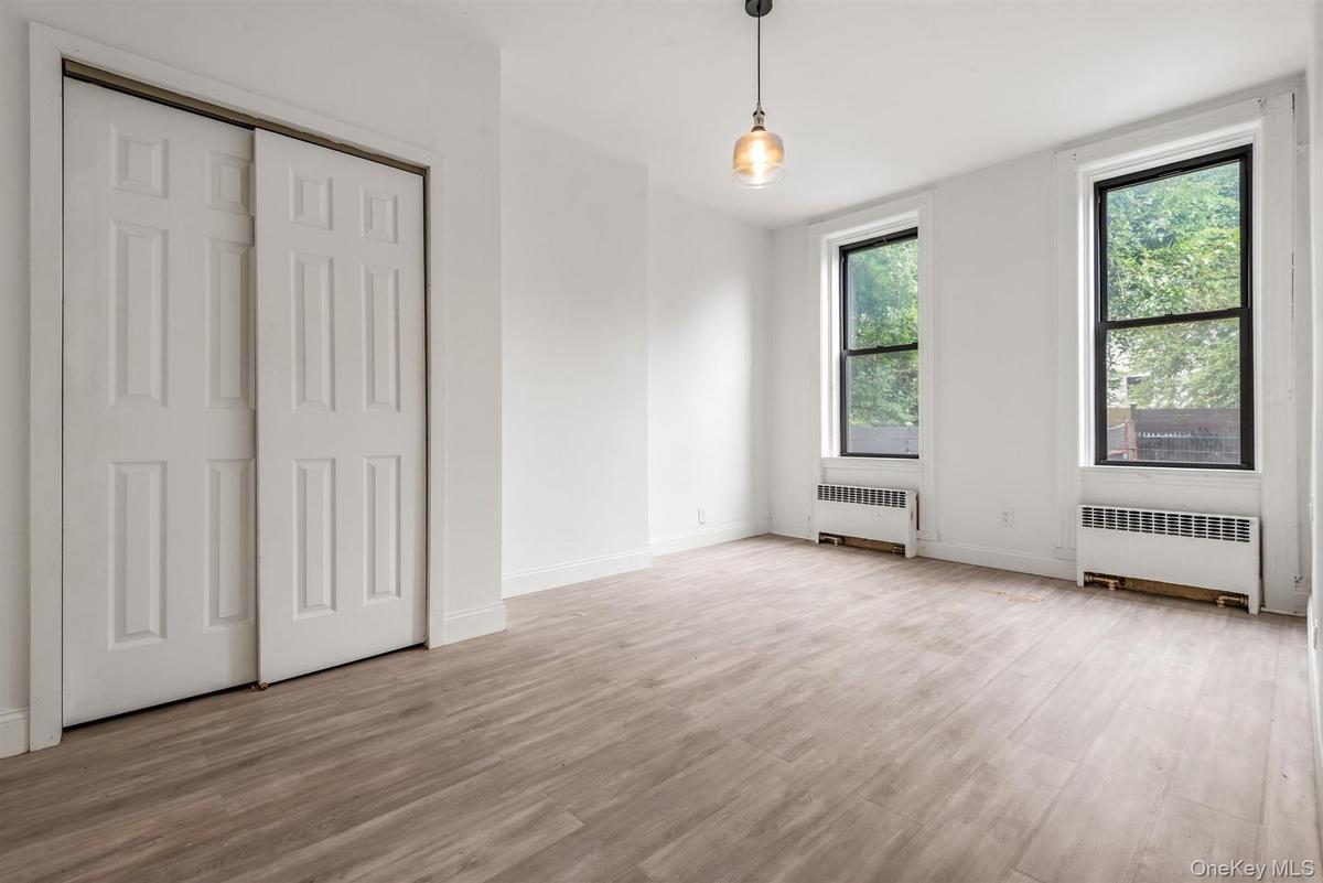 Unfurnished bedroom with radiator heating unit, light wood-style flooring, and a closet
