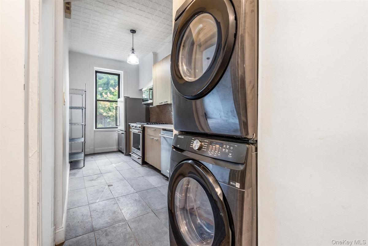 Laundry area featuring stacked washer / drying machine and light tile patterned floors