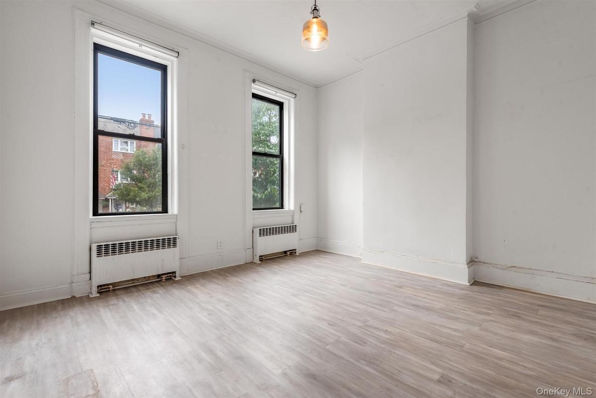 Empty room featuring light wood-style flooring, radiator heating unit, and crown molding