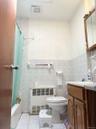 Bathroom with light tile patterned floors, tile walls, shower / bath combination with curtain, vanity, and radiator heating unit