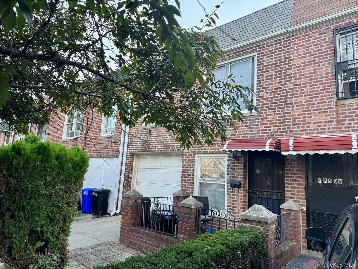 View of front of home featuring brick siding and roof with shingles
