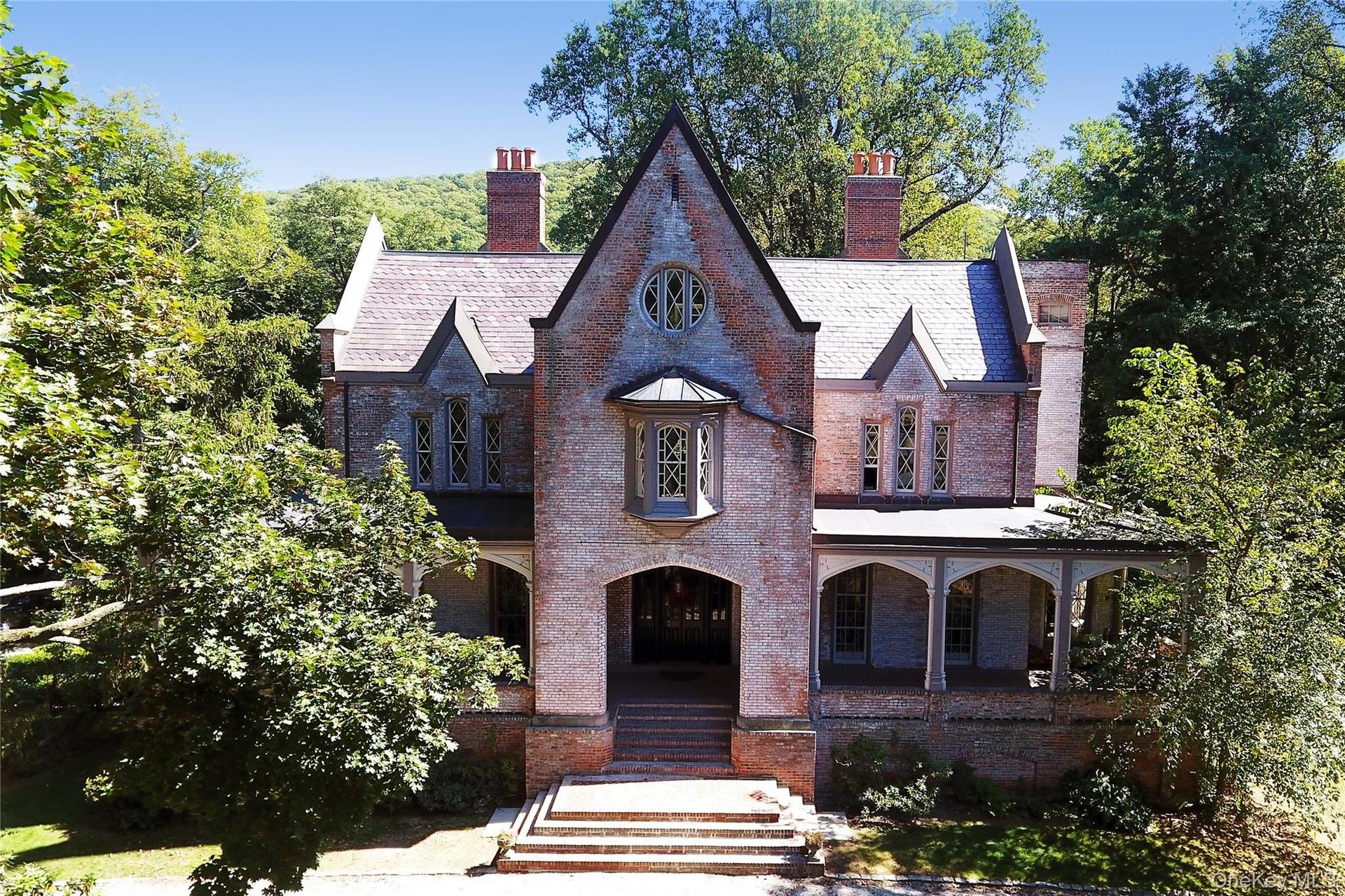 View of front facade featuring covered porch, brick siding, a chimney, and a high end roof