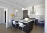 Kitchen featuring backsplash, a breakfast bar area, wall chimney range hood, dark brown cabinetry, and dark wood-type flooring