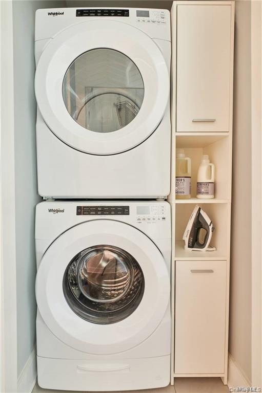 Laundry room featuring stacked washer / drying machine and tile patterned flooring