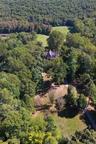 Aerial view of property and surrounding area with a forest