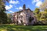Back of house with a lawn, a chimney, brick siding, and a balcony