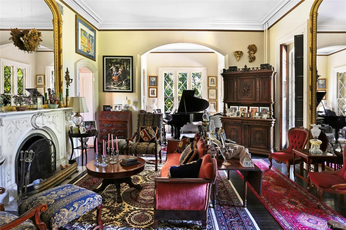 Sitting room featuring arched walkways, crown molding, plenty of natural light, and a fireplace with raised hearth