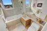 Full bath with a combined bath / shower with jetted tub, vanity, and light tile patterned floors